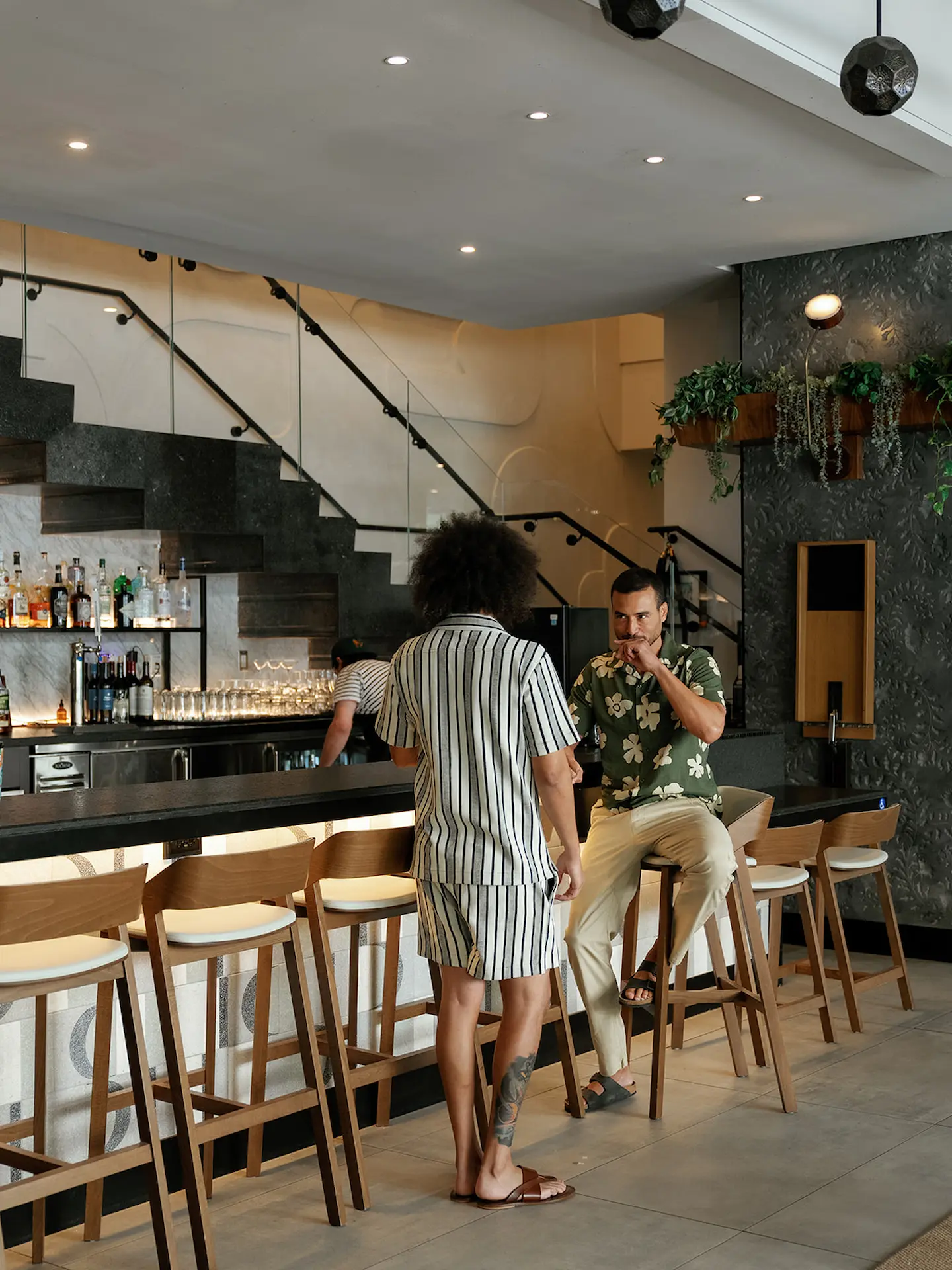 Two friends at the bar of The Café, enjoying drinks and sharing a lively conversation