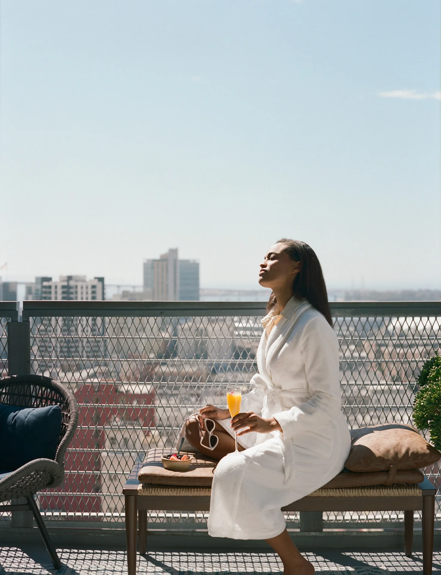 A woman on the balcony of the suite, soaking up the sun and enjoying a refreshing natural juice